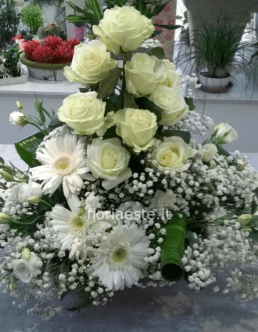 Composizione alta bianca con rose, gerbere, lisianthus, gypsophila e verdi pregiati di contorno.